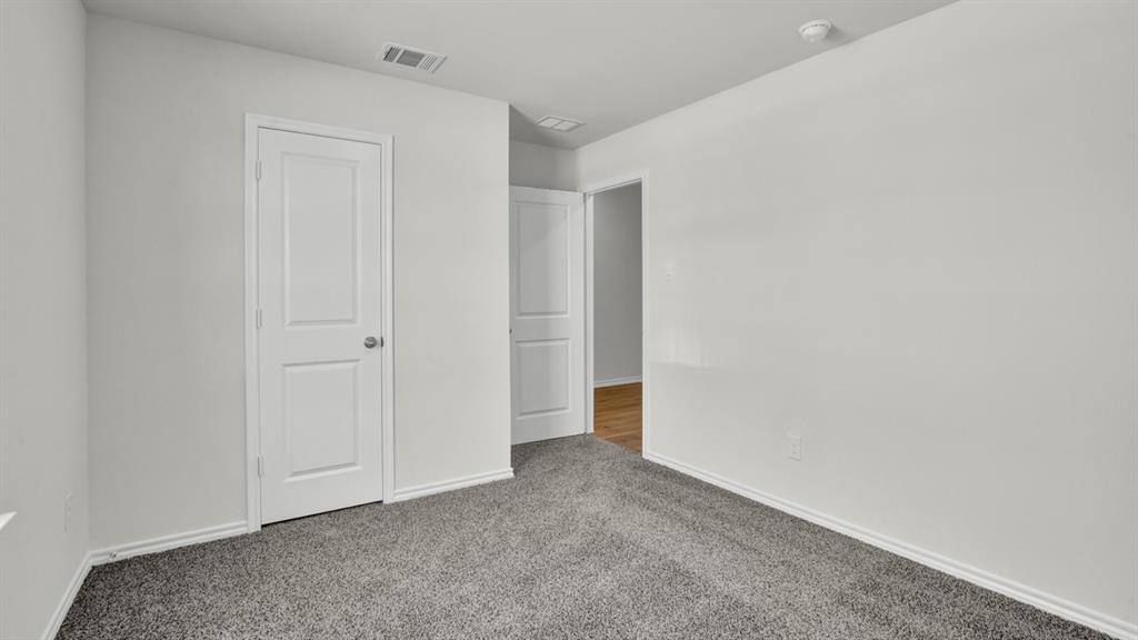 Carpeted interior space featuring light gray walls, white trim, and a paneled white door