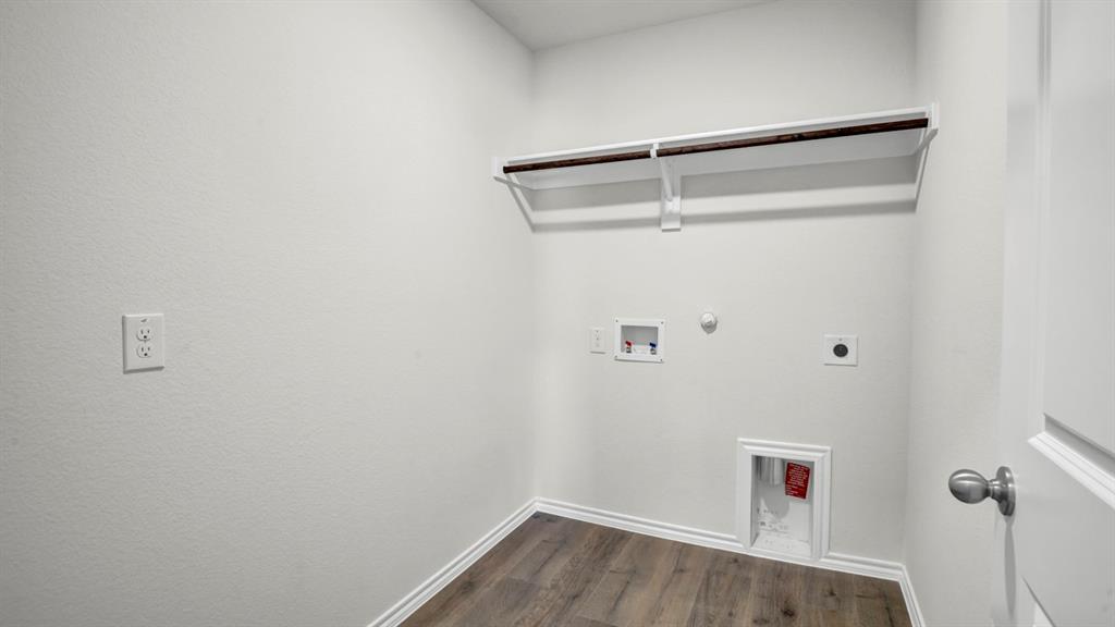 Dedicated laundry area featuring wood-finish flooring, white baseboards, and a clothing rod with shelving