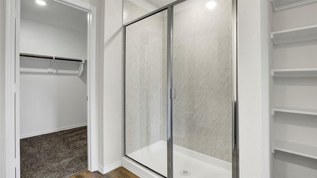 Walk-in shower with sliding glass doors, white shower pan, and grey-patterned tile surround