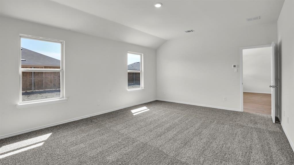 Spacious room featuring gray textured carpet and bright white walls