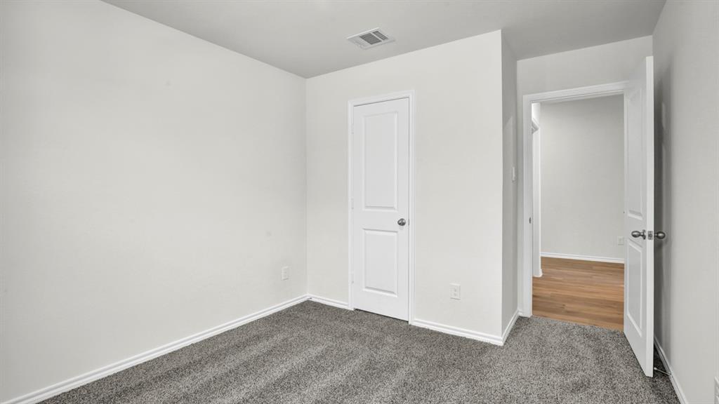Carpeted room featuring white walls, white trim, and a white paneled door with a silver-tone knob