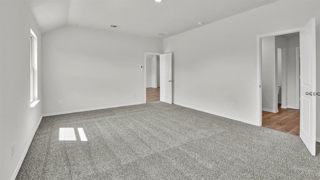 Spacious room featuring vaulted ceilings, light gray carpeting, and white walls