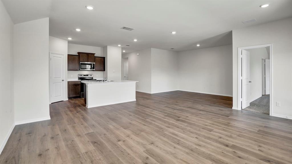 Expansive open-concept living area featuring wood-finish flooring, recessed lighting, and a kitchen with dark wood cabinetry