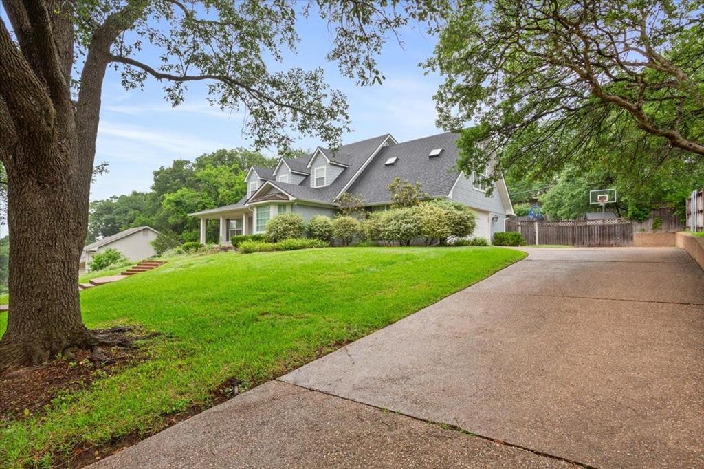 Traditional-style residence featuring a prominent front porch with columns, dormer windows, and a dark shingle roof Traditional-style residence featuring a prominent front porch with columns, dormer windows, and a dark shingle roof