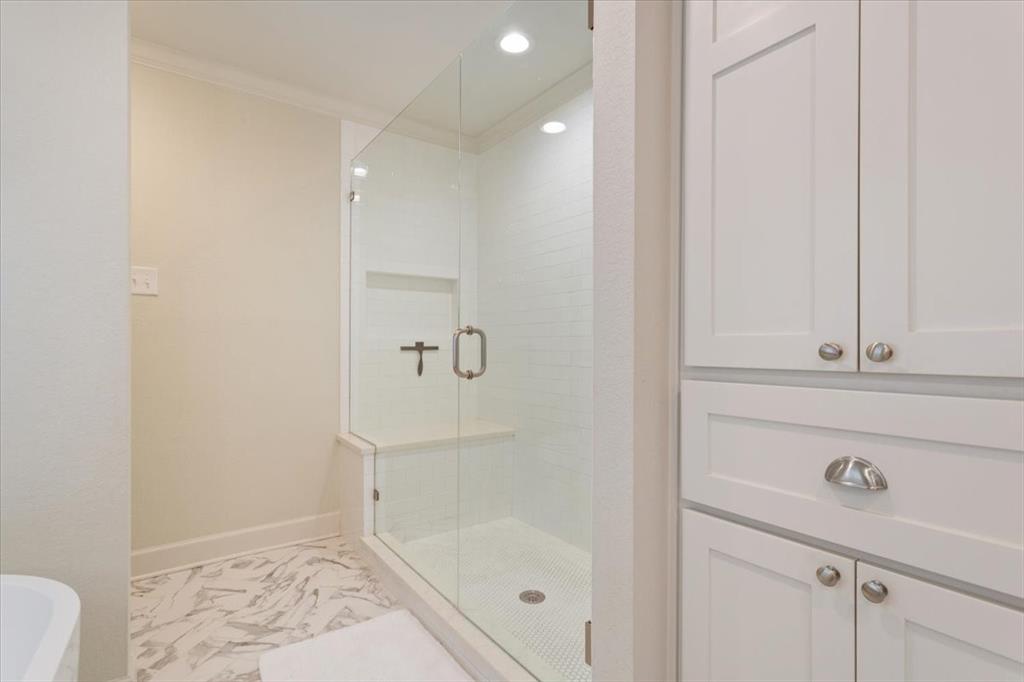 Upstairs glass-enclosed shower with a built-in bench and recessed shelving