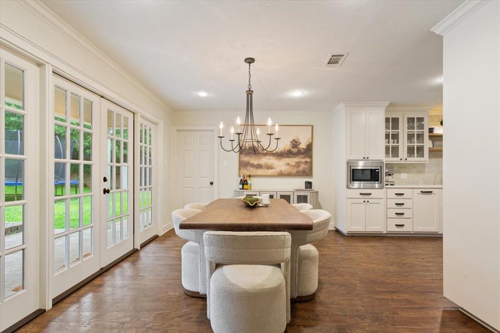 Dining area featuring wood-finish flooring, two sets of French patio doors, and an adjacent built-in serving area with white cabinetry and a built-in microwave
