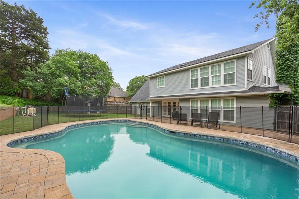 Kidney-shaped swimming pool featuring a paver surround