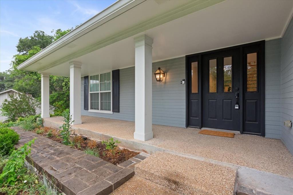 Covered front porch featuring white columns and an exposed aggregate surface Covered front porch featuring white columns and an exposed aggregate surface