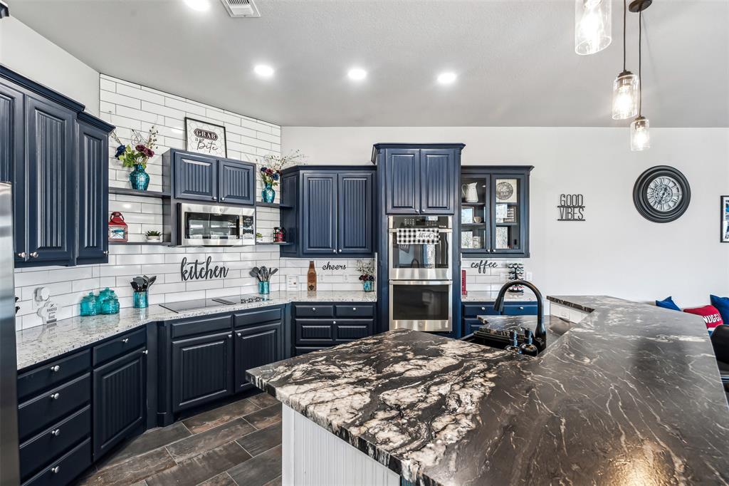 Spacious kitchen featuring dark cabinetry, two-tone countertops, a subway tile backsplash, and built-in stainless steel appliances