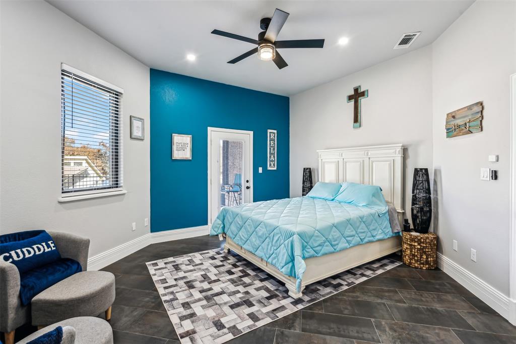 Room featuring dark tile flooring, a vibrant accent wall, a ceiling fan with integrated lighting, recessed lighting, and a private exterior door