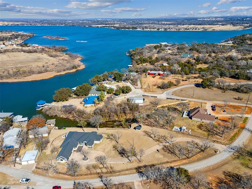 Aerial overview of a waterfront community featuring a large body of water, multiple residential properties, and a natural landscape
