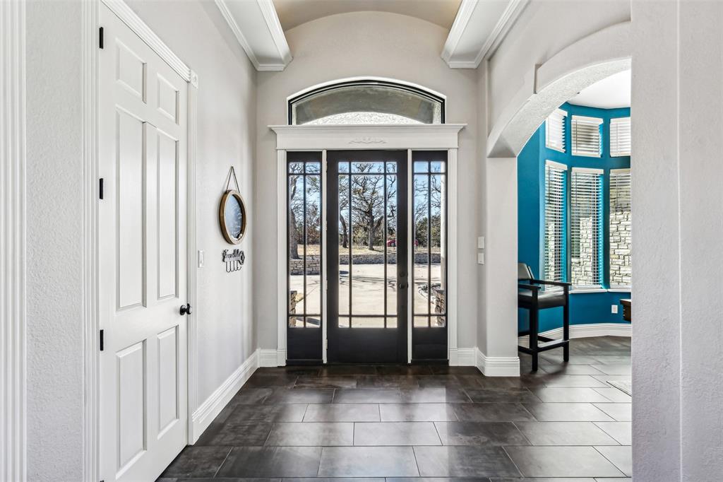 Grand entry featuring dark-framed French doors with an arched transom, leading to an exterior stone facade