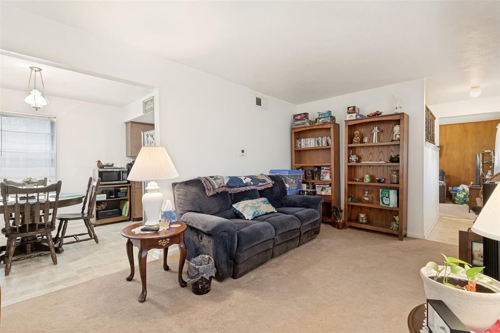 Carpeted living area with white walls and overhead lighting