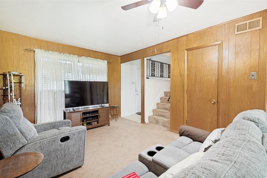 Living area featuring wood-paneled walls and carpeted flooring