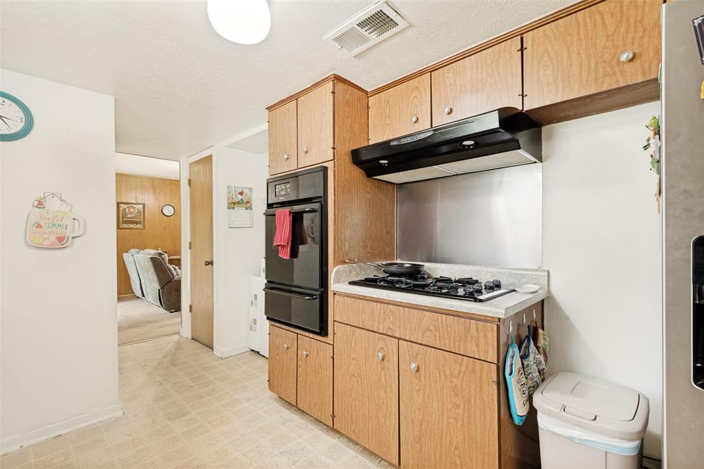 Kitchen featuring wood-finish cabinetry, a built-in double oven, and a gas cooktop with an overhead range hood