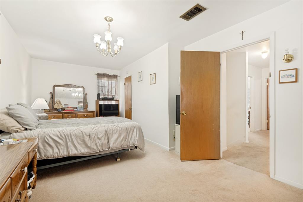 Carpeted room featuring a ceiling-mounted chandelier light fixture and a wood-panel interior door