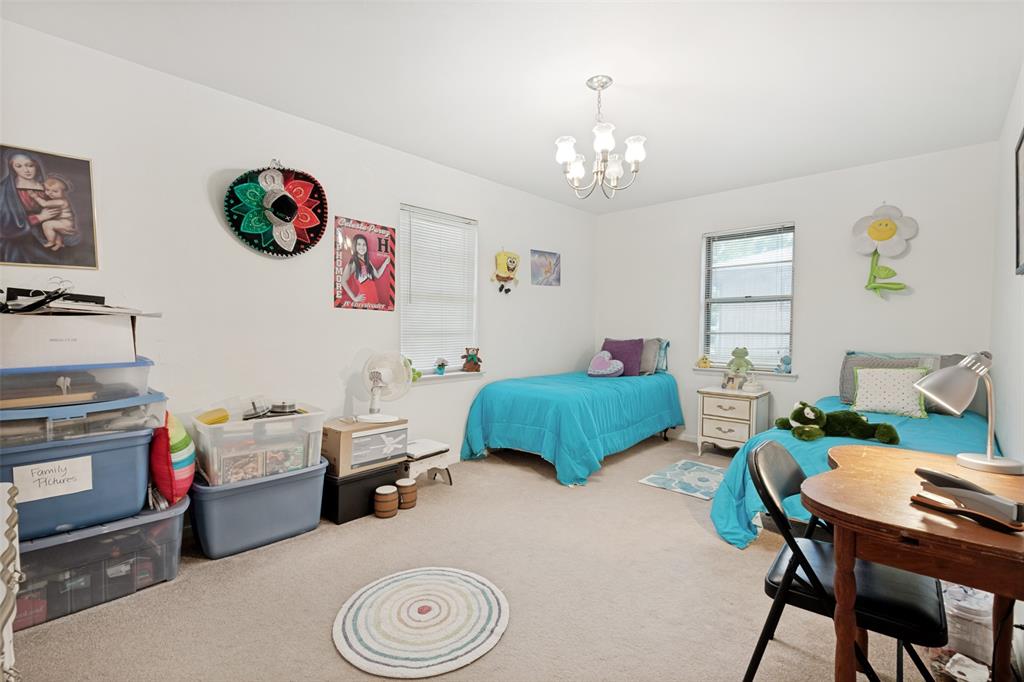 Bright room featuring a ceiling-mounted chandelier, carpeted flooring, and two windows providing natural light