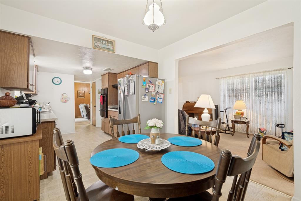 Dining area featuring a central wooden table, wood-finish flooring, and an overhead pendant light fixture