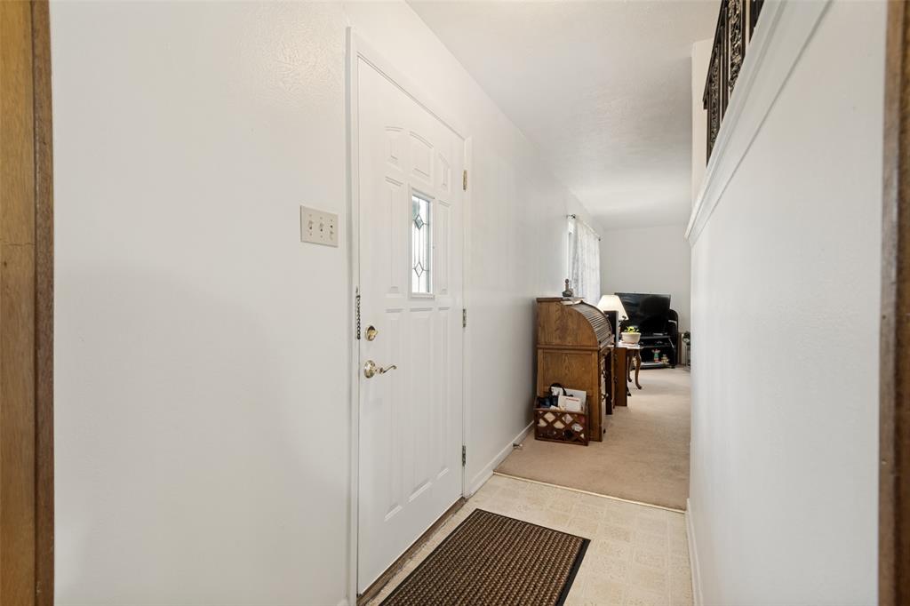 Entryway with a paneled white door featuring a decorative glass insert and brass hardware