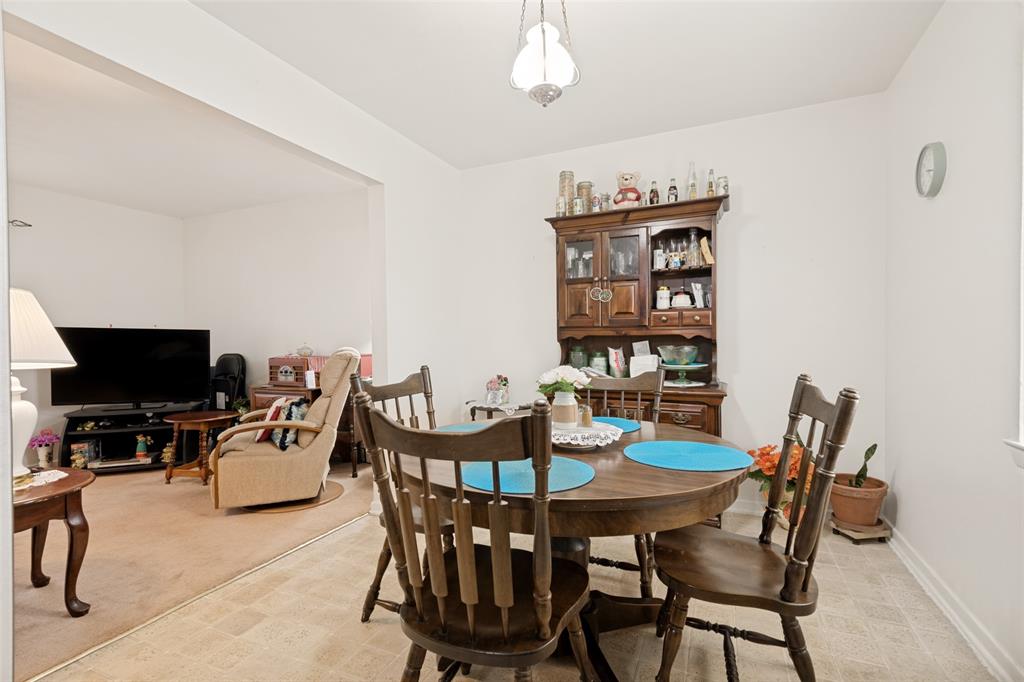 Dining area featuring neutral vinyl flooring, a cased opening, and a built-in wood hutch with glass doors