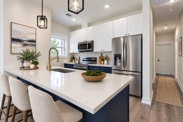 Virtual staging - Kitchen featuring a white countertop island, stainless steel appliances, white upper cabinetry, and blue lower cabinetry Virtual staging - Kitchen featuring a white countertop island, stainless steel appliances, white upper cabinetry, and blue lower cabinetry