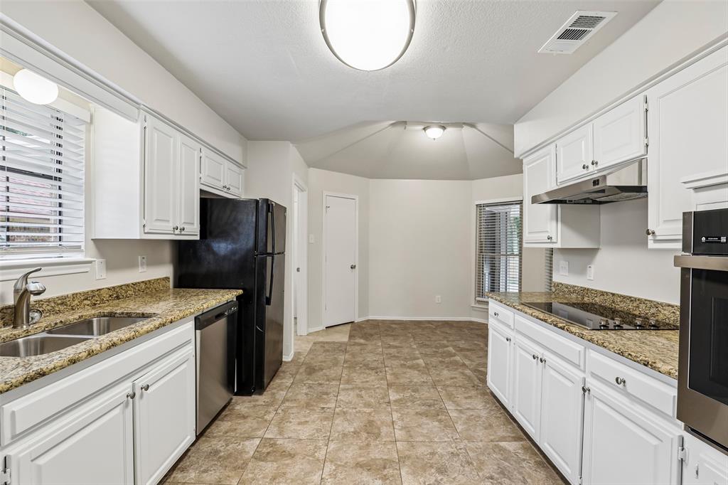 Kitchen featuring white cabinetry, granite-style countertops, stainless steel sink, tile flooring, and integrated stainless steel appliances