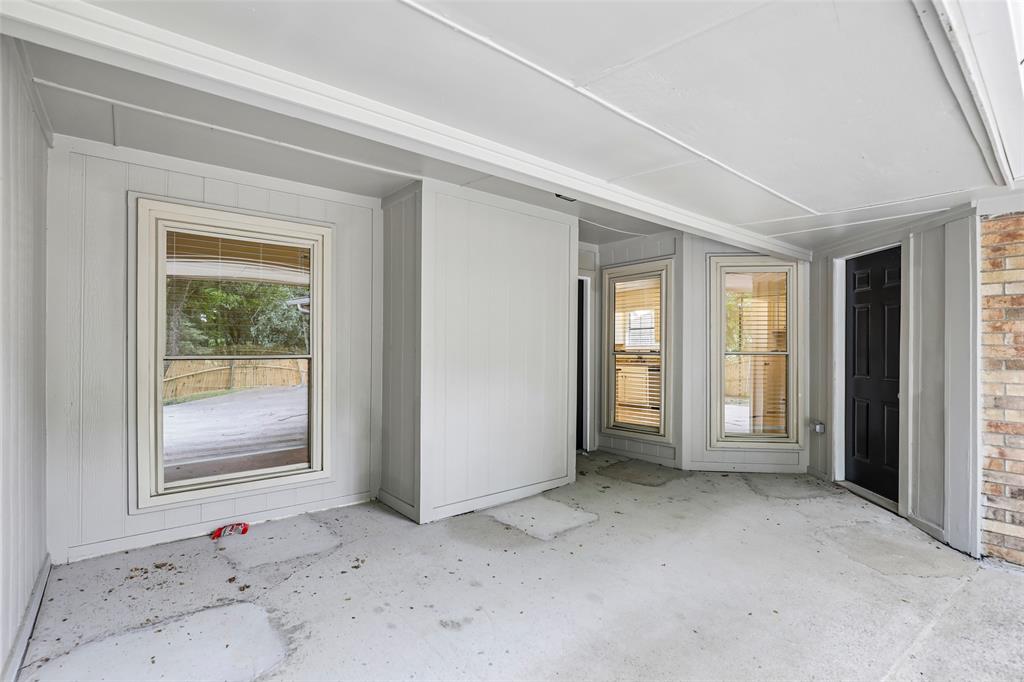Covered patio with a concrete slab floor, light gray vertical paneling, and multiple windows with blinds