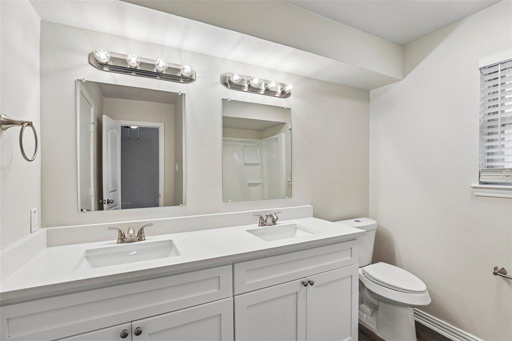 Dual vanity with white cabinetry, integrated sinks, brushed nickel fixtures, and coordinating wall-mounted light bars