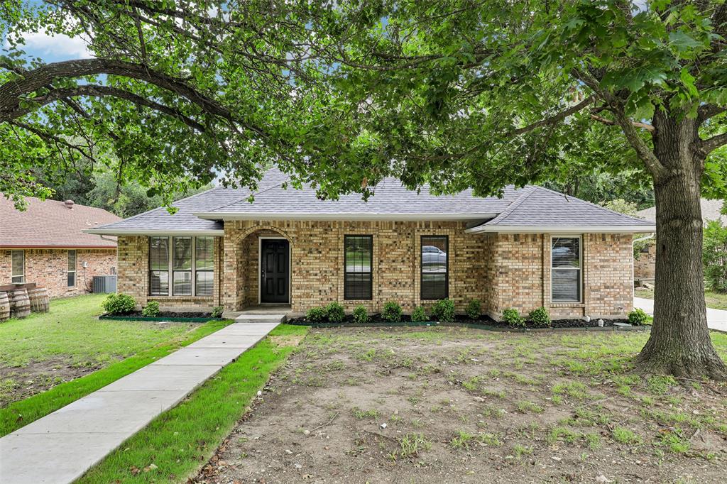 Brick exterior home featuring a dark shingle roof, black entry door, and multi-pane windows Brick exterior home featuring a dark shingle roof, black entry door, and multi-pane windows