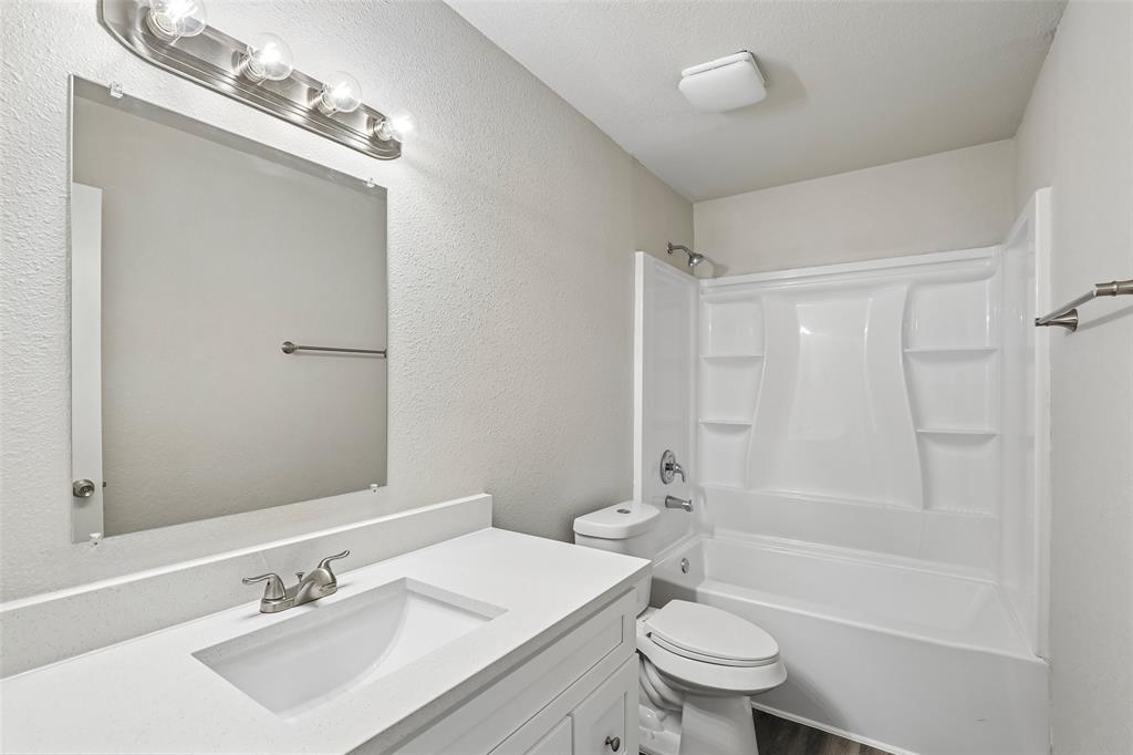 Bathroom featuring a white vanity with an integrated sink, brushed nickel faucet, and a large mirror