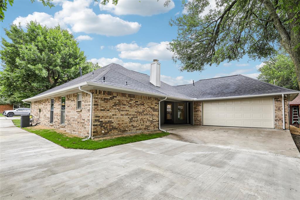 Exterior brick facade with a two-car garage, concrete driveway, and dark shingle roof