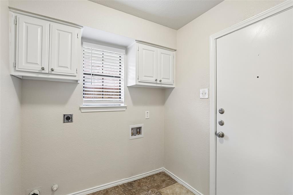 Laundry area featuring overhead cabinetry, a window with blinds, and utility connections