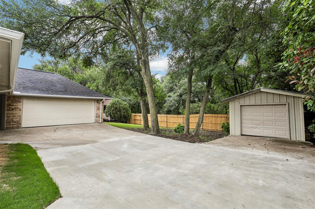 Expansive concrete driveway with a two-car garage and a detached single-car garage