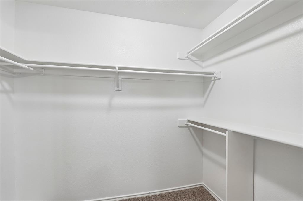 Walk-in closet featuring white wire shelving, hanging rods, and neutral-toned carpet flooring
