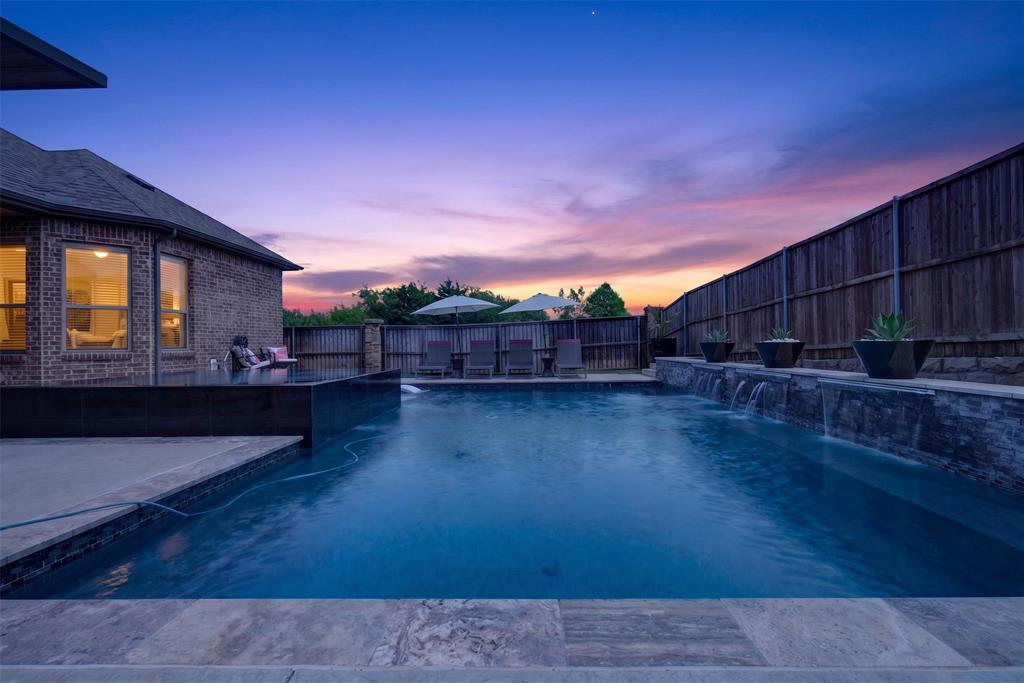 Pool and spa are framed by the covered patio and beautifully lit outdoor living space.