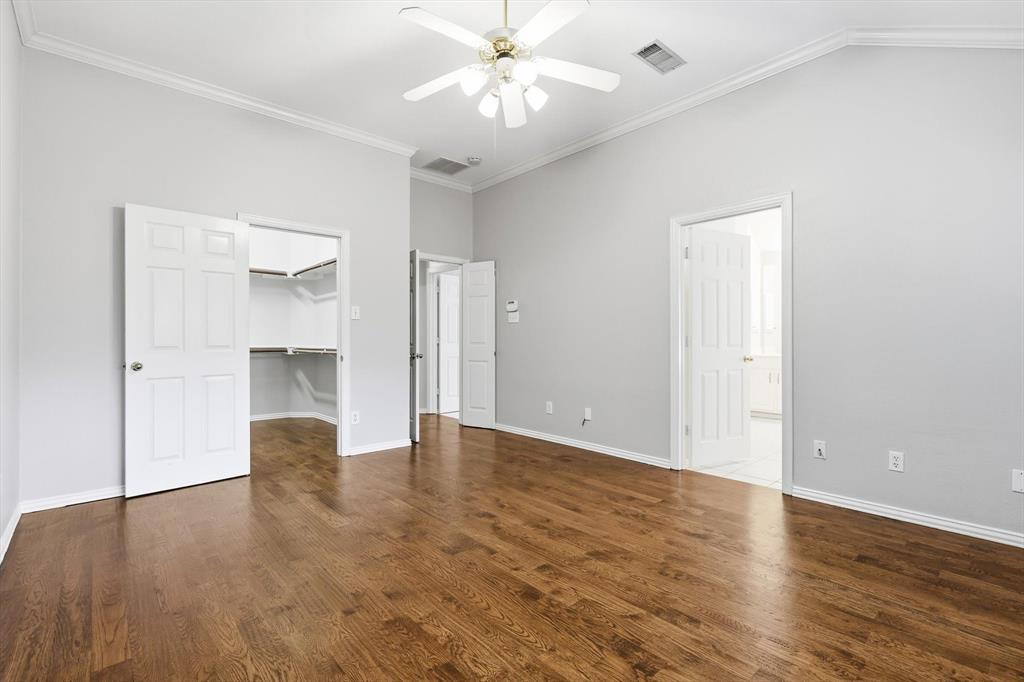 Spacious room featuring wood-finish flooring, vaulted ceilings, and a ceiling fan