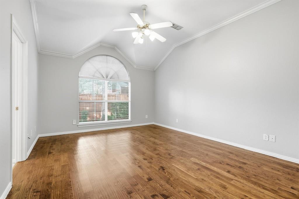 Vaulted ceiling room featuring wood-finish flooring, an arched window with blinds, and a ceiling fan with light fixture