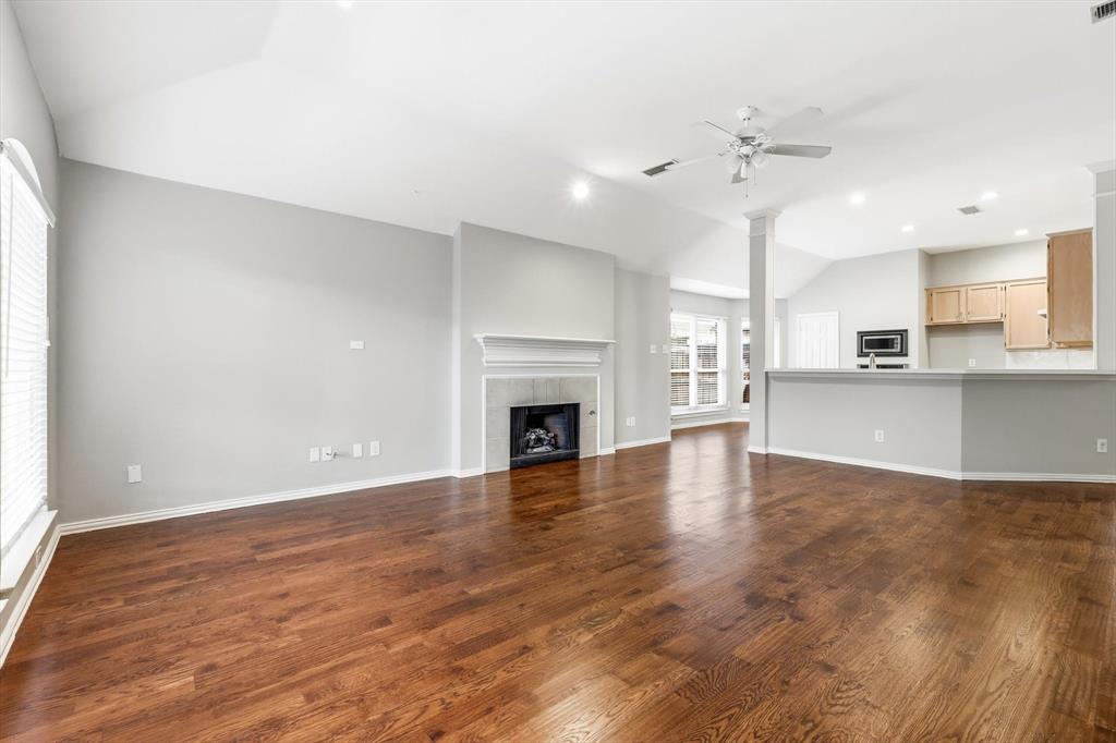 Expansive living space featuring wood-finish flooring, a fireplace with a mantel, vaulted ceilings, a ceiling fan, and recessed lighting