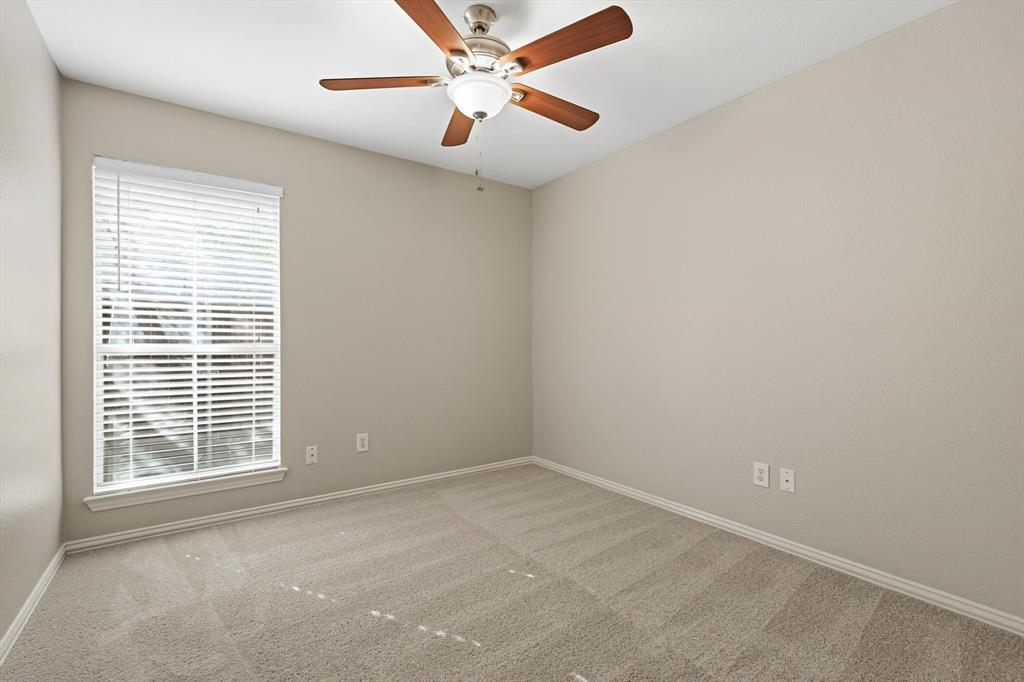 Room featuring neutral carpeting, a large window with horizontal blinds, and a ceiling fan with integrated lighting