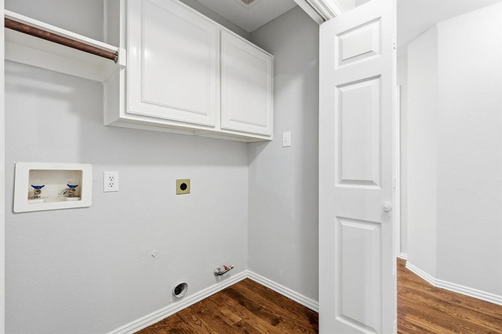 Dedicated laundry area featuring white shaker-style cabinetry, a built-in hanging rod, utility hookups, and wood-finish flooring