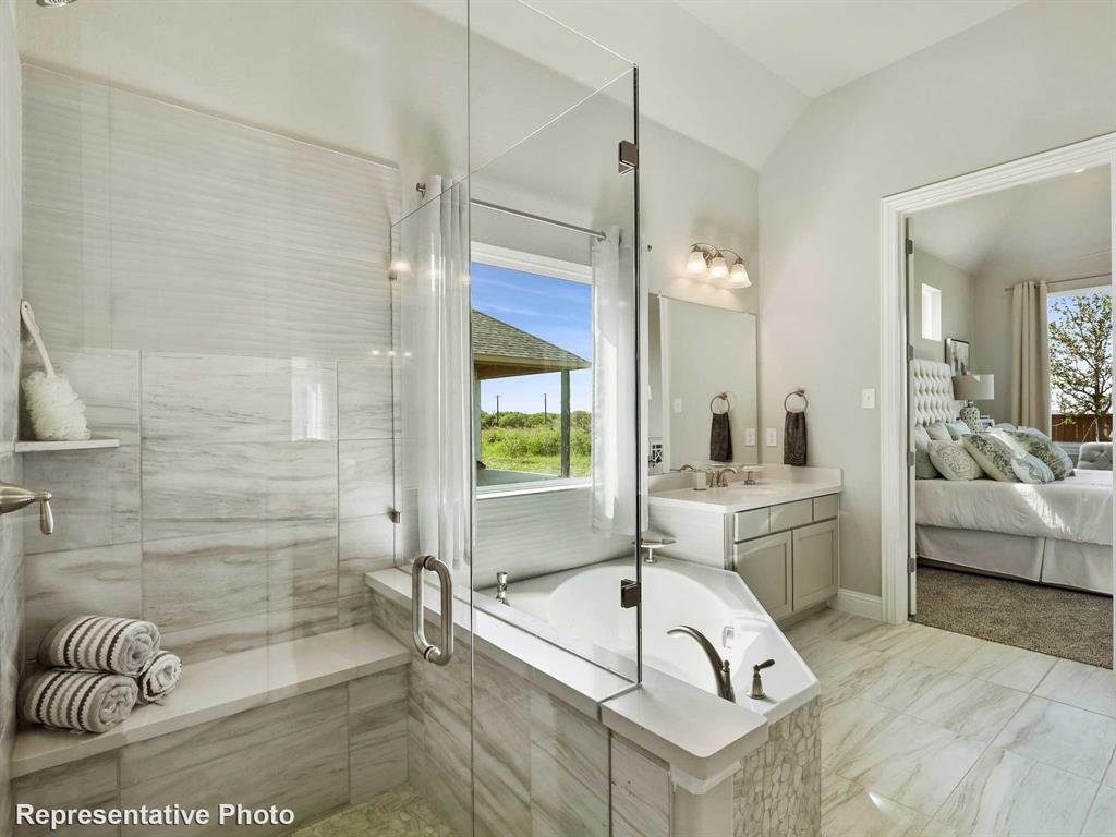 Bathroom featuring a built-in soaking tub, a frameless glass shower enclosure with a built-in bench, a dual vanity with a built-in mirror, and light-toned tile flooring