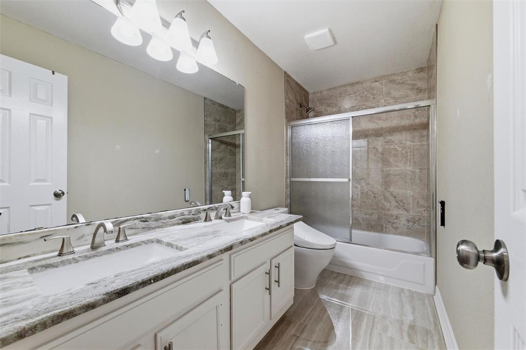 Hall Bath Up with dual sinks, marble counters, floor and tub shower surround with glass enclosure, upgraded bidet commode.