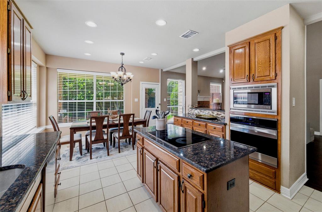 Island has smooth cooktop, stainless steel built in microwave and wall oven.