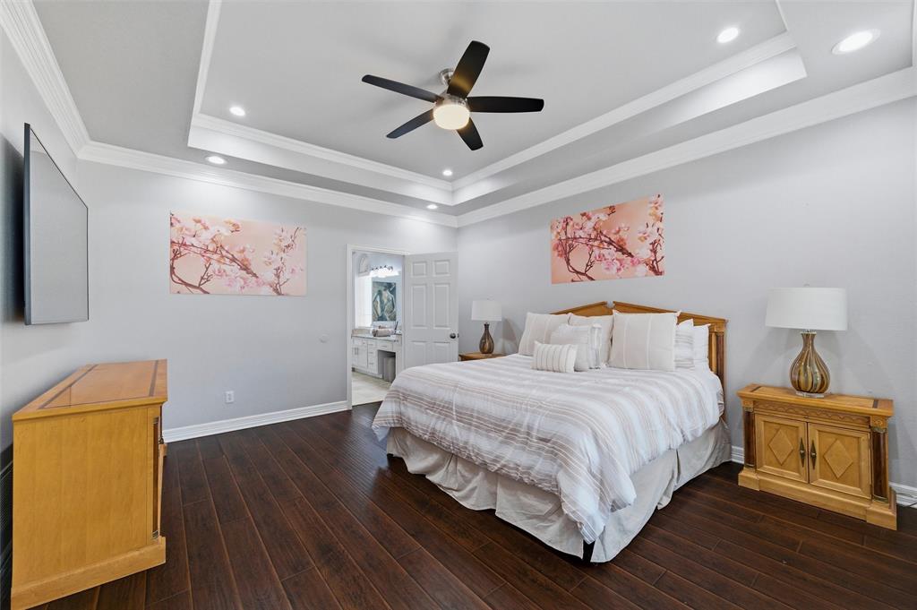 Primary Bedroom with engineered wood, ceiling fan, tray ceiling with crown molding, and recessed lighting.