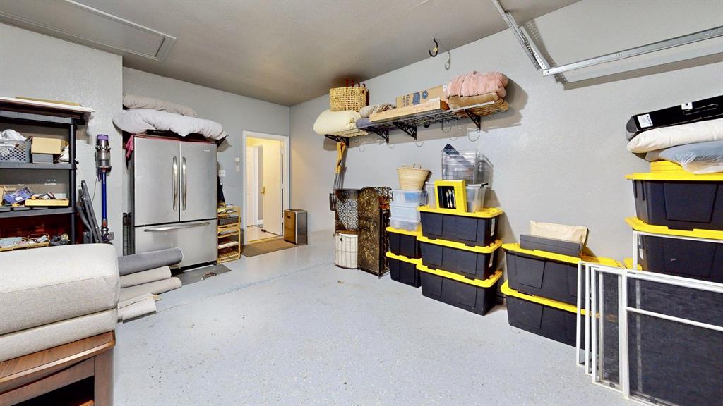 Garage has recent garage door replacement, epoxy finish, walls and ceiling paint, Tesla charger, and wall rack storage system.