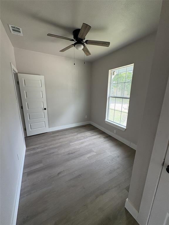 Neutral-toned interior featuring wood-finish flooring, a ceiling fan with light, and a paneled door