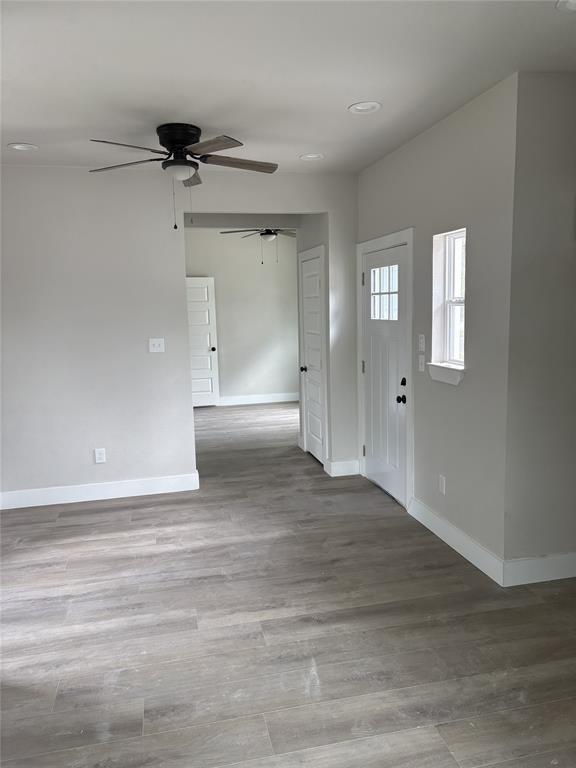 Light-filled interior featuring wood-finish flooring, recessed lighting, ceiling fan, white baseboards, and a paneled front door with divided lites