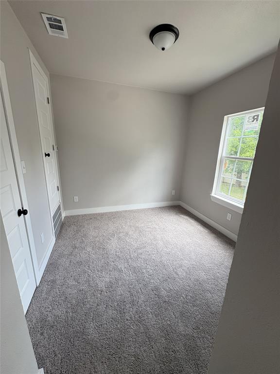 Neutral-toned room featuring a single window, two panel doors, and a ceiling-mounted light fixture