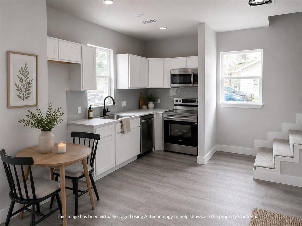 Modern kitchen featuring white cabinetry, stainless steel appliances, a light-toned backsplash, light wood-finish flooring, and recessed lighting