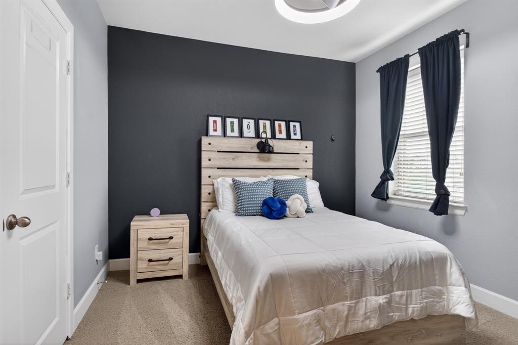 Third bedroom featuring a stylish accent wall and abundant natural light, creating a warm and inviting retreat.